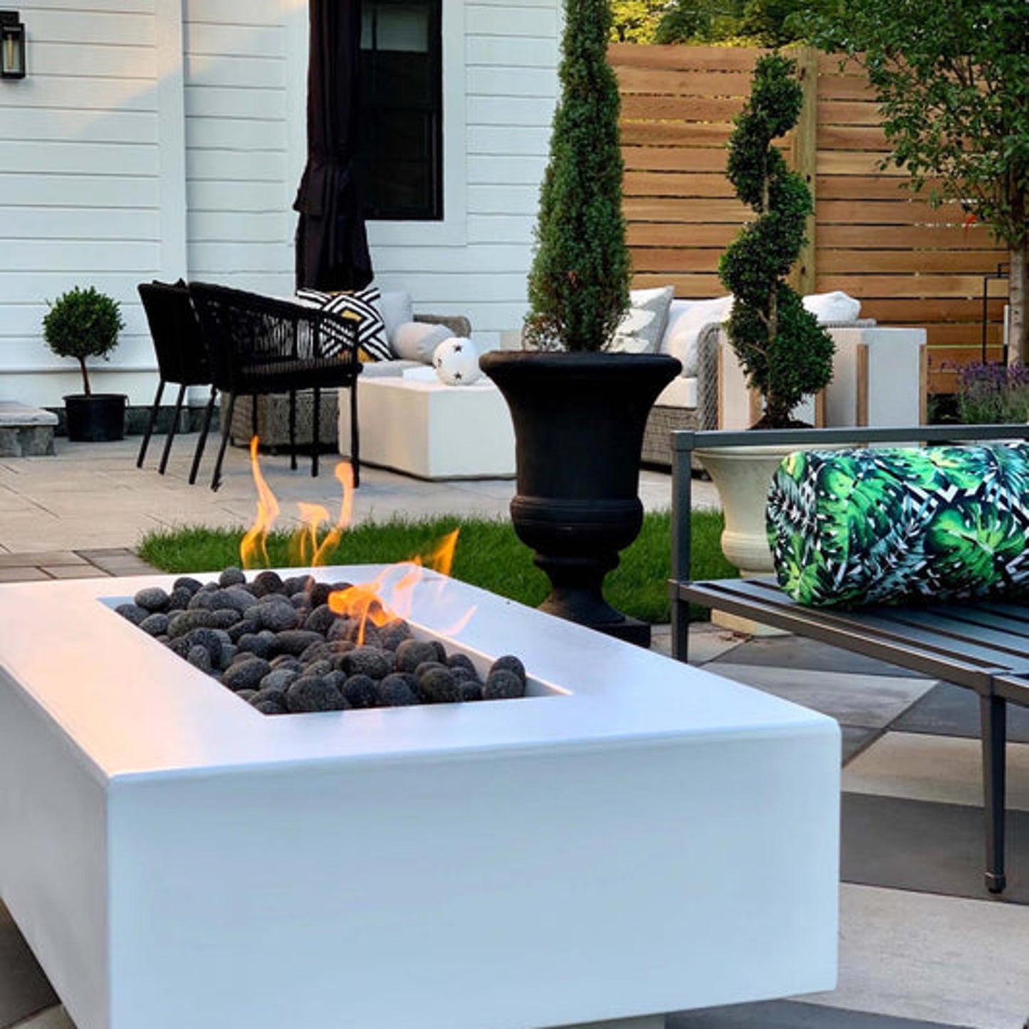 Del Mar 48 inch concrete rectangular fire pit in Limestone finish with flames in outdoor setting by The Outdoor Plus
