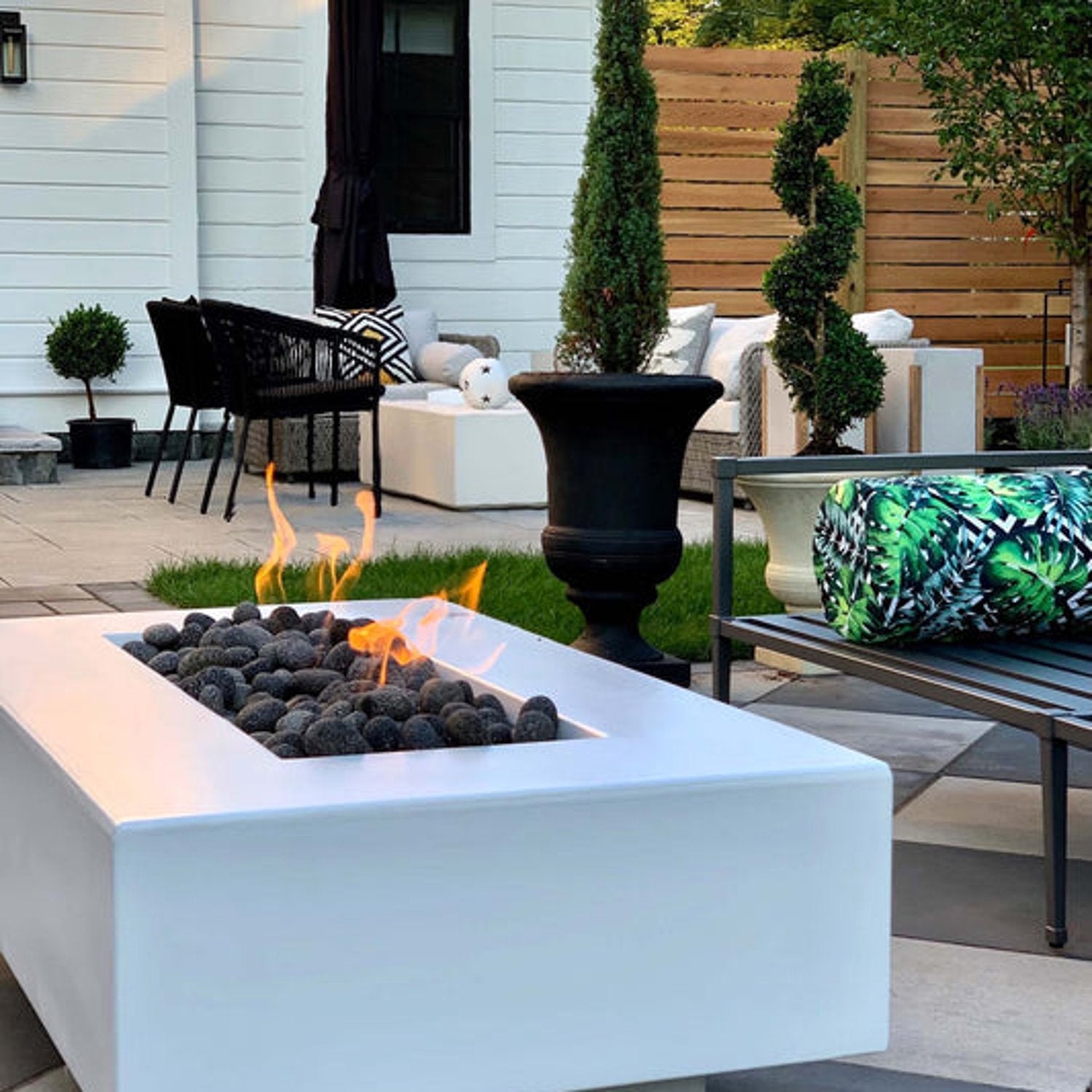 Del Mar 48 inch concrete rectangular fire pit in Limestone finish with flames in outdoor setting by The Outdoor Plus
